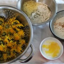 ingredients for dandelion fritters laid out: dandelion flowers, batter, egg, etc.