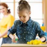 Image of a girl helping to keep the home clean by spraying a counter with cleaner and a cloth.