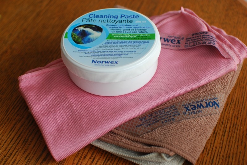 norwex cleaning paste and window and body cloths on a wooden surface