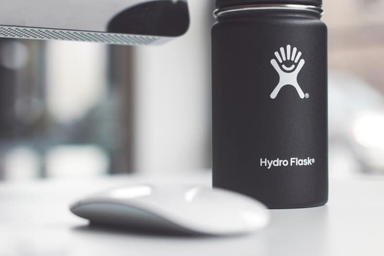 close up of black hydroflask water bottle gift for dad sitting next to a computer and mouse