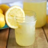 small jar of homemade lemonade with lemons in background