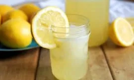 small jar of homemade lemonade with lemons in background