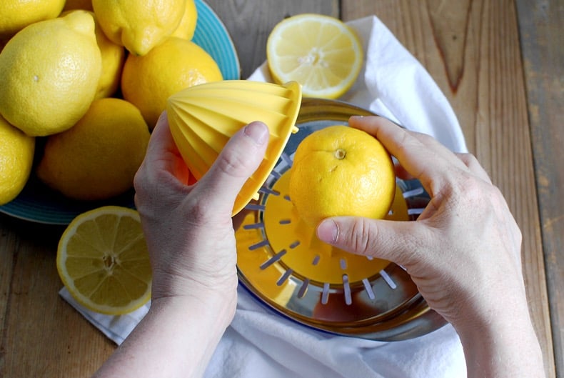 hands juicing a lemon with a manual juicer