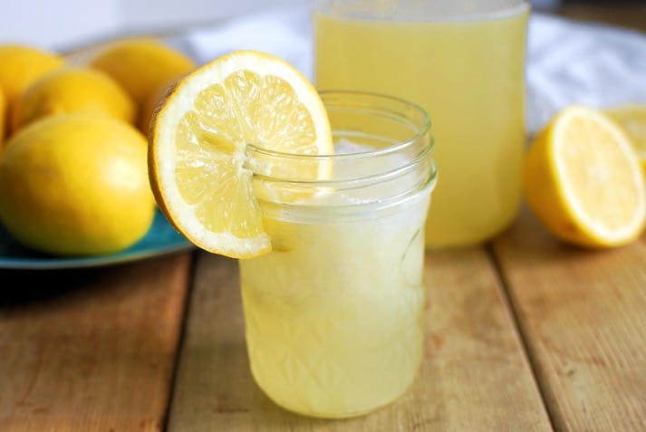 small jar of homemade lemonade with lemons in background