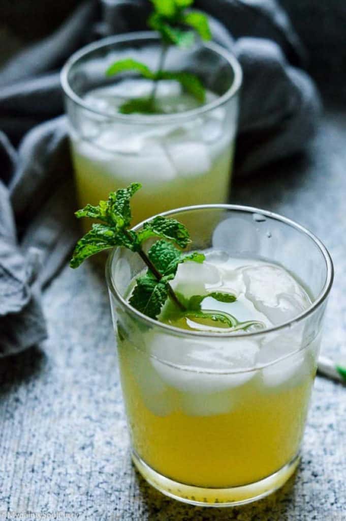two glasses of green iced tea with sprigs of mint to garnish cups