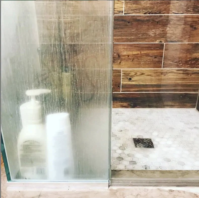 glass shower wall and door half with soap scum, and half cleaned with norwex window cloth