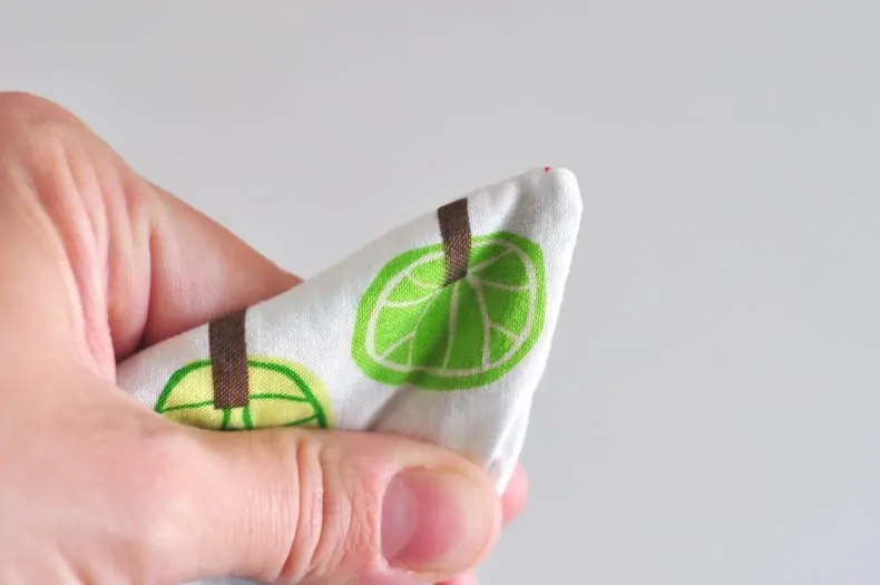 Hands hold the completed bag and show pushing out the corners with the eraser end of a pencil