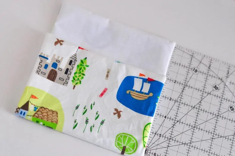 Fabric rectangle has been laid out on a surface against a ruler. The bottom has been folded up to the point that leaves a 2" flap to be folded over.