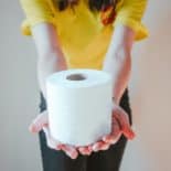 girl holding roll of toilet paper and wearing a yellow shirt