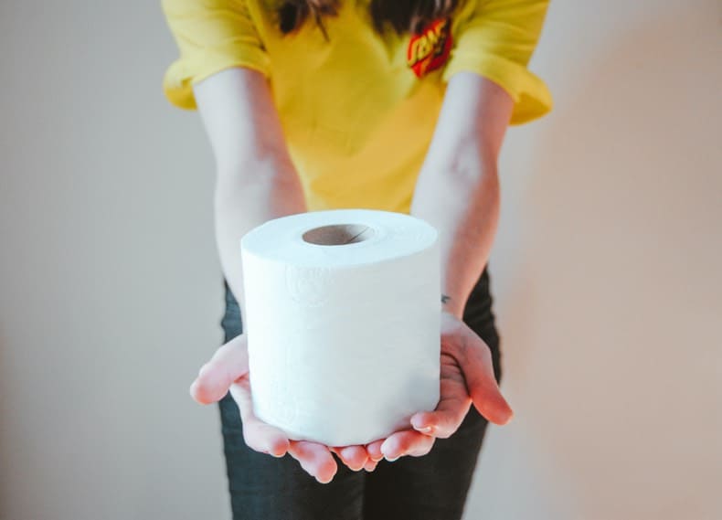 girl holding roll of toilet paper and wearing a yellow shirt