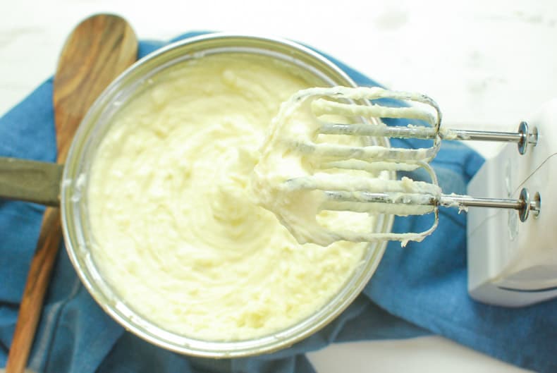 Pot of creamy mashed potatoes with hand mixer. 