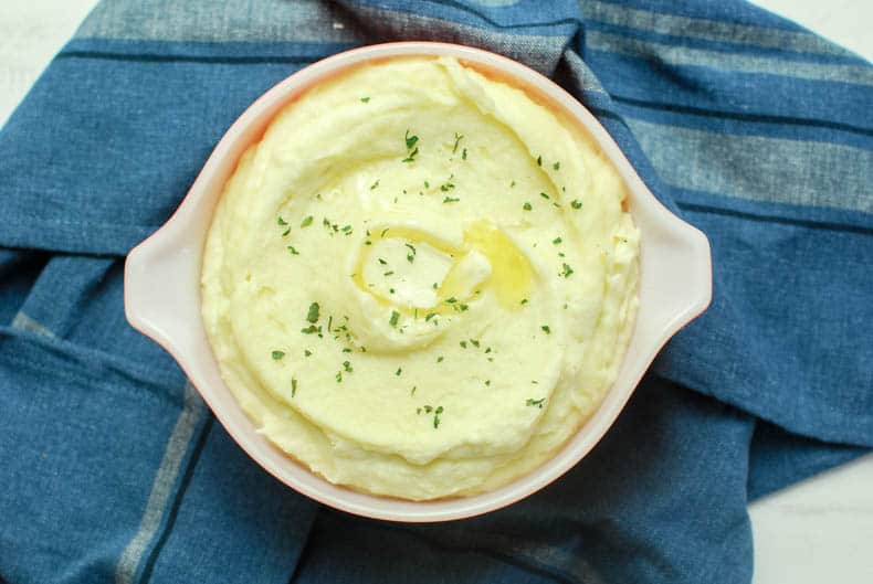 Overhead shot of creamy mashed potatoes in a serving dish with butter.