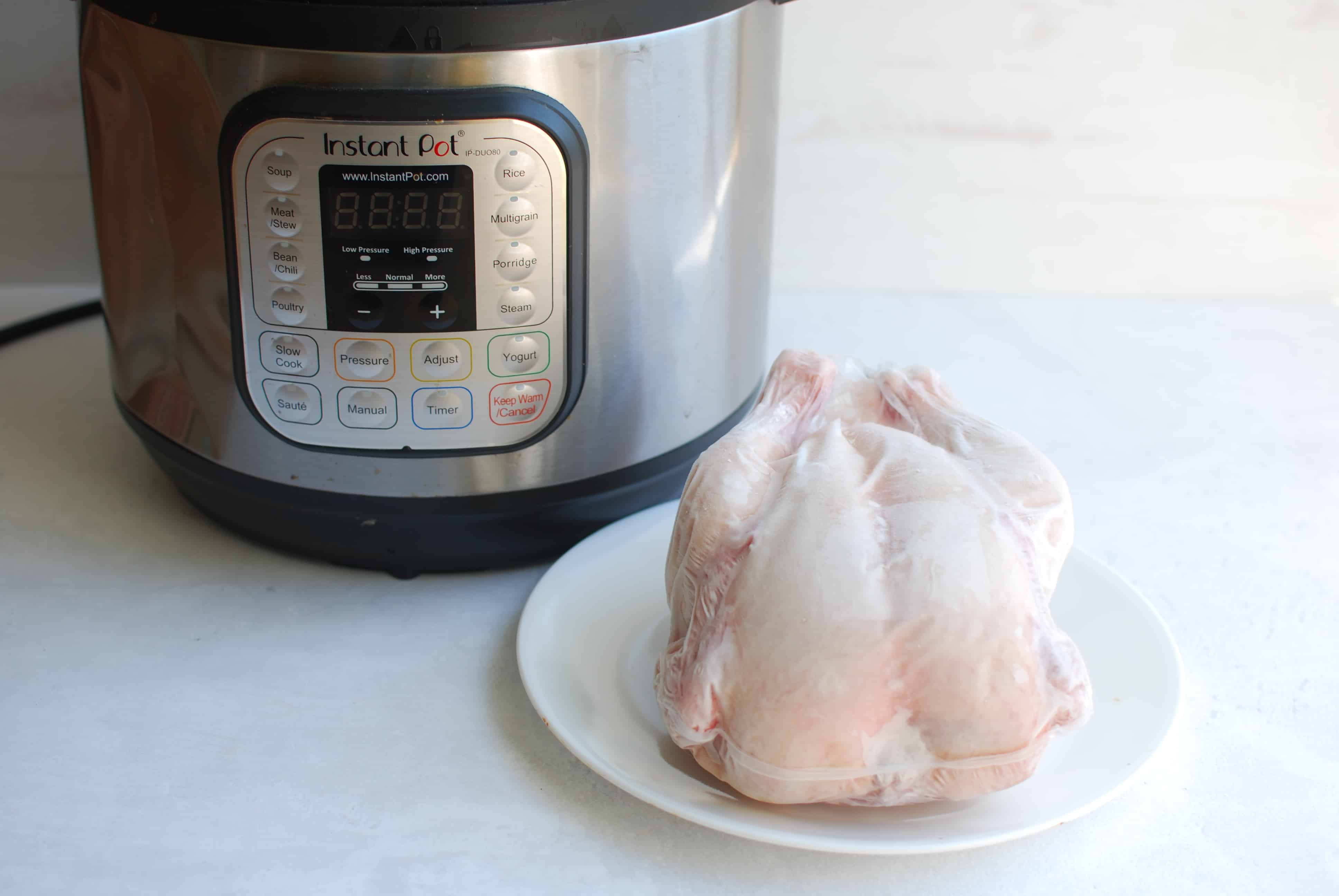 frozen whole chicken sitting in front of an instant pot on a countertop