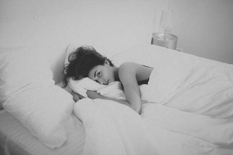 Woman lying in bed in black and white, with anxiety at night and trouble sleeping