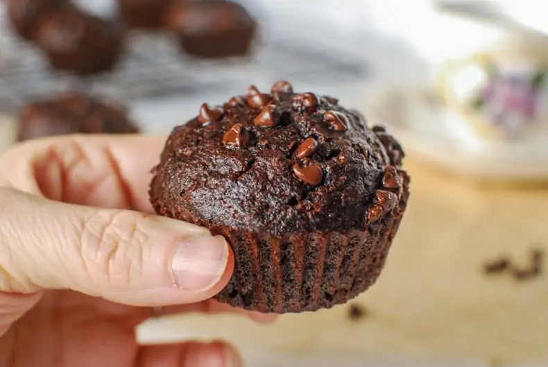 a close up shot of a coconut flour chocolate muffin being held up to the camera