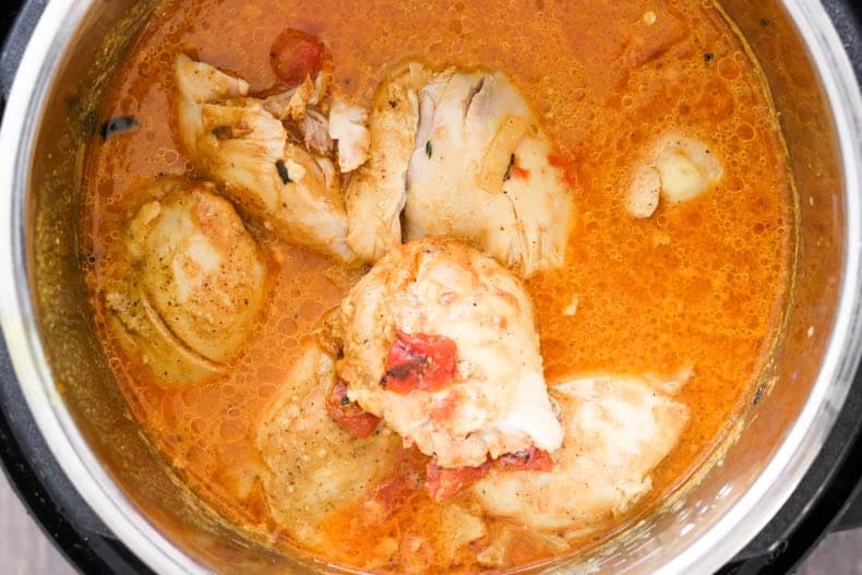 overhead view of instant pot chicken curry still in the pot, just finished cooking in a rich, tomato coconut spicy cream sauce