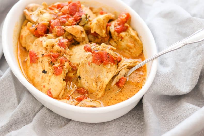 serving bowl of instant pot chicken curry on a grey linen surface