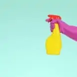 a blue background with a pink-gloved arm holding out a yellow spray bottle for spring cleaning
