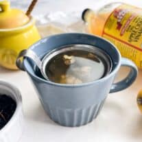 a blue mug with debloating tea with apple cider vinegar, lemon, ginger, and green tea.