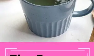 An image of a blue mug of tea with a hand adding apple cider vinegar with a measuring spoon.