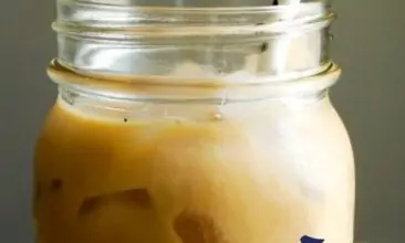 a pin image with a close up shot of iced chai latte with text overlay in black, blue, and green