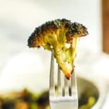 A perfectly crispy piece of air fryer broccoli held up on a fork.