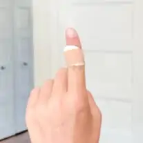 one finger up with a wart bandaid with apple cider vinegar, with a plain background in a home