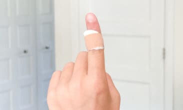 one finger up with a wart bandaid with apple cider vinegar, with a plain background in a home